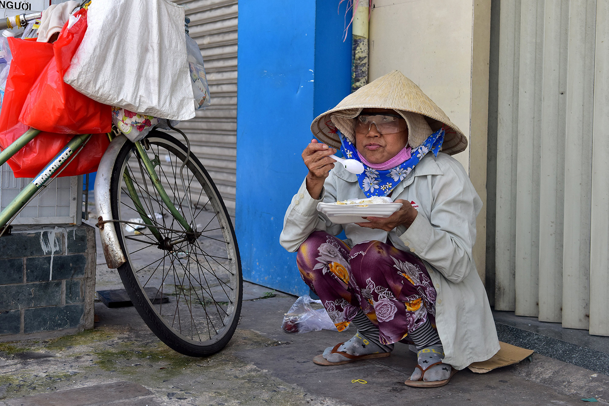 Ngay sau khi nhận cơm, nhiều người ngồi ăn tại chỗ ngay bên vỉa hè. “Nhiều ngày qua người làm nghề ve chai đi nhặt thì không có, chủ vựa cũng đóng nên hầu như thất nghiệp như nhiều người khác. Những suất cơm miễn phí của chú Dũng và những người làm từ thiện khác phát cho nên cũng đỡ được được phần nào”, người phụ nữ nhặt ve chai cho hay.