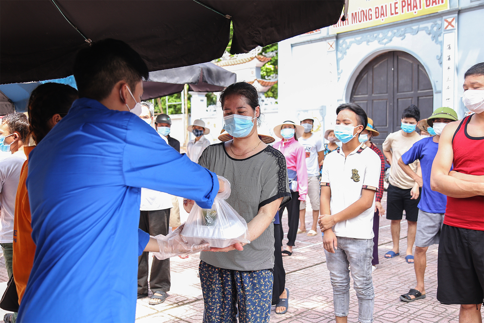 Từng người vào lấy cơm dưới sự hướng dẫn, sắp xếp của lực lượng thanh niên, đảm bảo an toàn và khoảng cách phòng dịch.