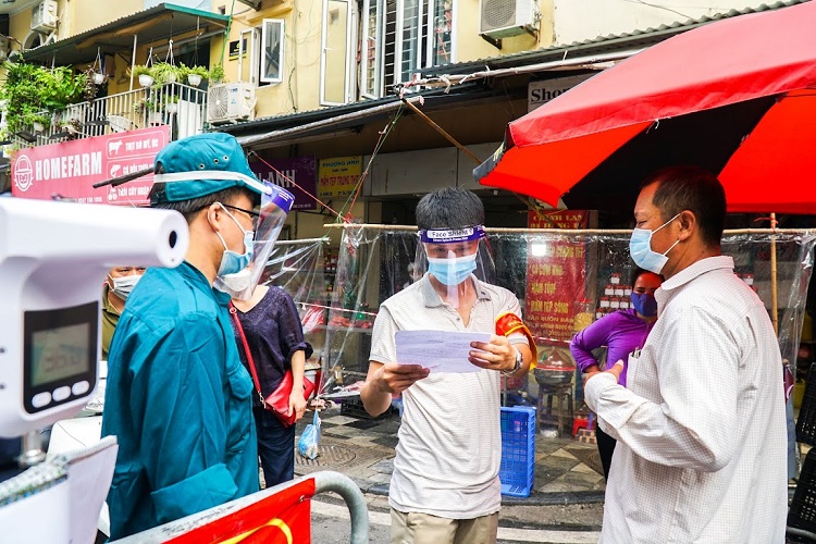 Để vào chợ, người dân ở phường Hàng Bạc phải trình phiếu đi chợ, đúng ngày và đúng địa chỉ nhà, sau đó được đo thân nhiệt, khử khuẩn tay.