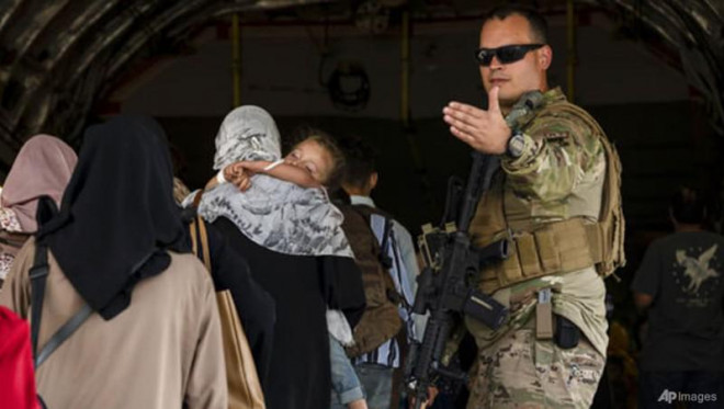 Binh sĩ Mỹ hỗ trợ người dân lên máy bay sơ tán. Ảnh: AP