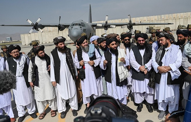 Phát ngôn viên Taliban Zabihullah Mujahid, trả lời họp báo tại sân bay Kabul. Phía sau là chiếc máy bay C-130 do Mỹ bỏ lại.