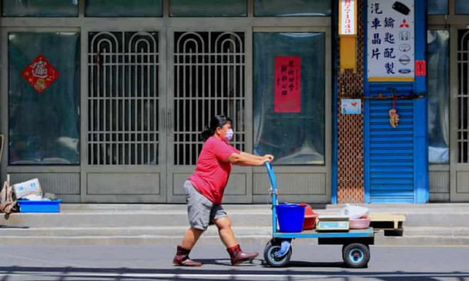 Người phụ nữ đeo khẩu trang đẩy xe đồ ở Bình Đông, Đài Loan. Ảnh: THE GUARDIAN