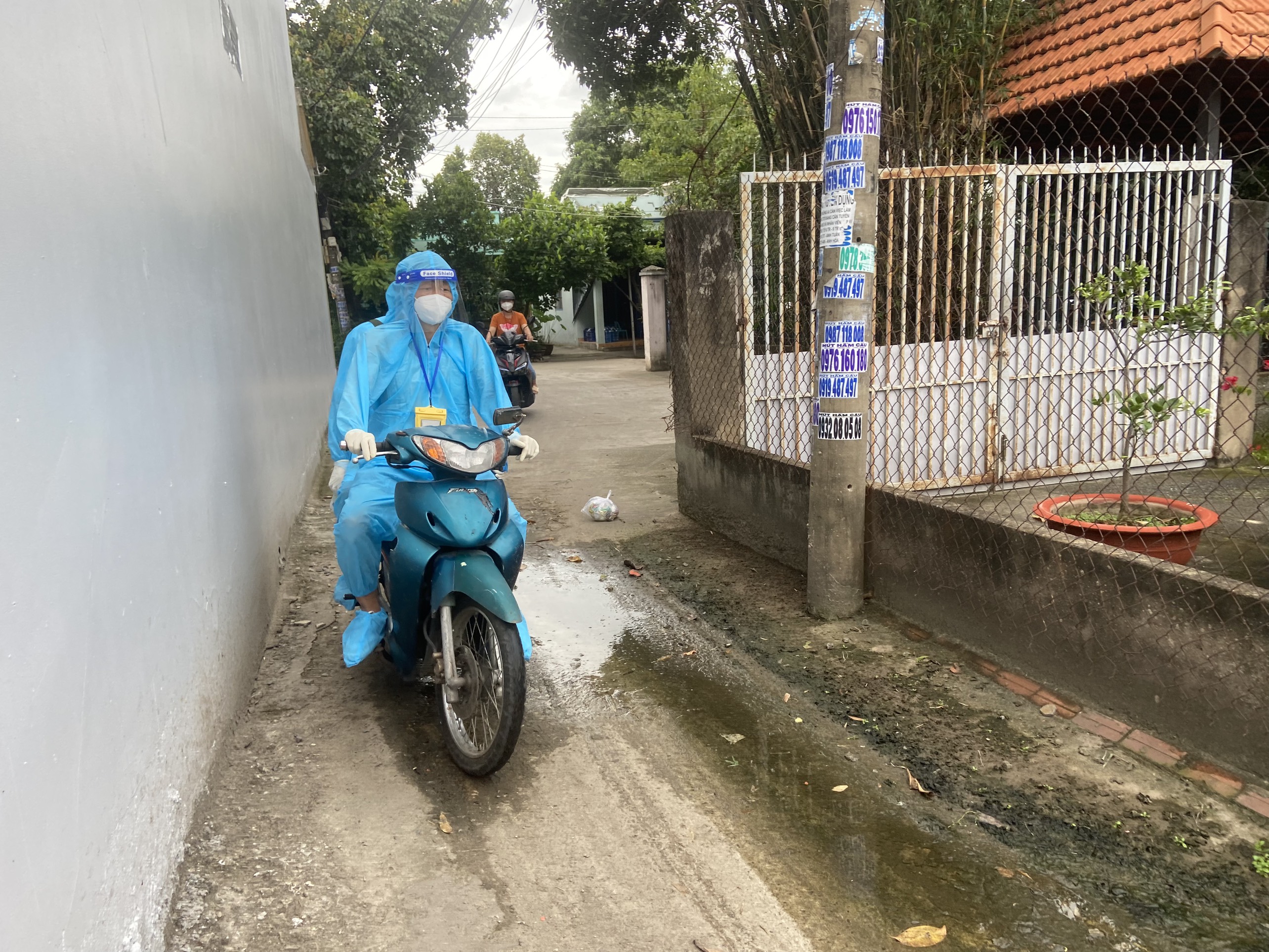 Đội tiêm vắc xin di chuyển bằng xe máy len lỏi vào tận các con hẻm sâu để đến nhà người dân.