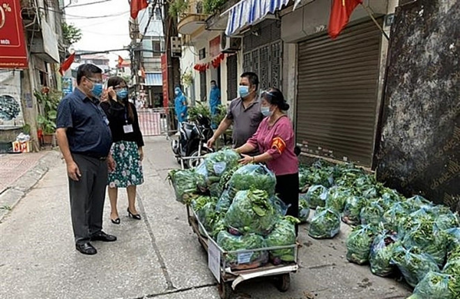 Phó Chủ tịch UBND quận Hoàn Kiếm Nguyễn Anh Quân và Bí thư Đảng ủy phường Chương Dương Trần Thị Thanh Vân kiểm tra công tác vận chuyển hàng hóa lương thực, thực phẩm trong khu phong tỏa cách ly y tế (Ảnh: TTXVN)