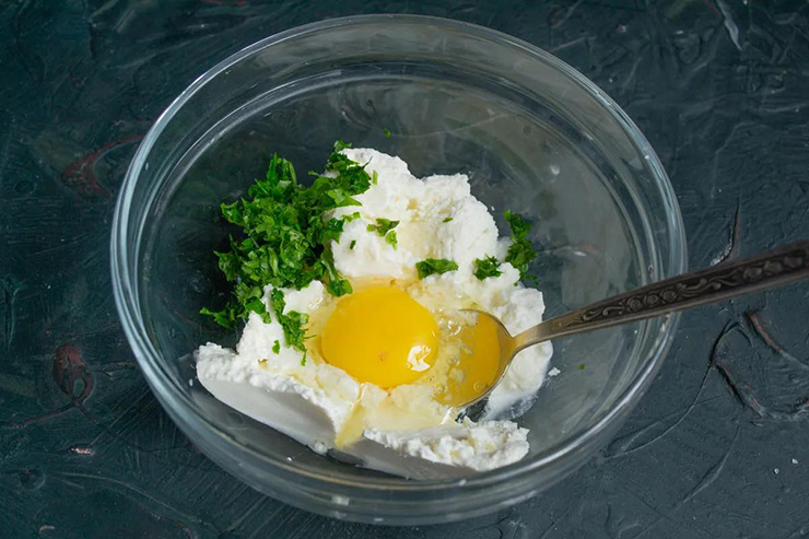 Cho phô mai ricotta tươi, trứng, rau mùi tây, muối và hạt tiêu vào tô trộn đều.