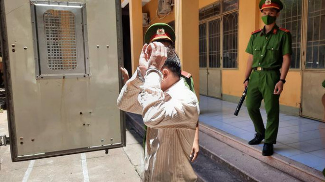 Bị cáo Việt đưa tay che mặt khi thấy phóng viên chụp ảnh