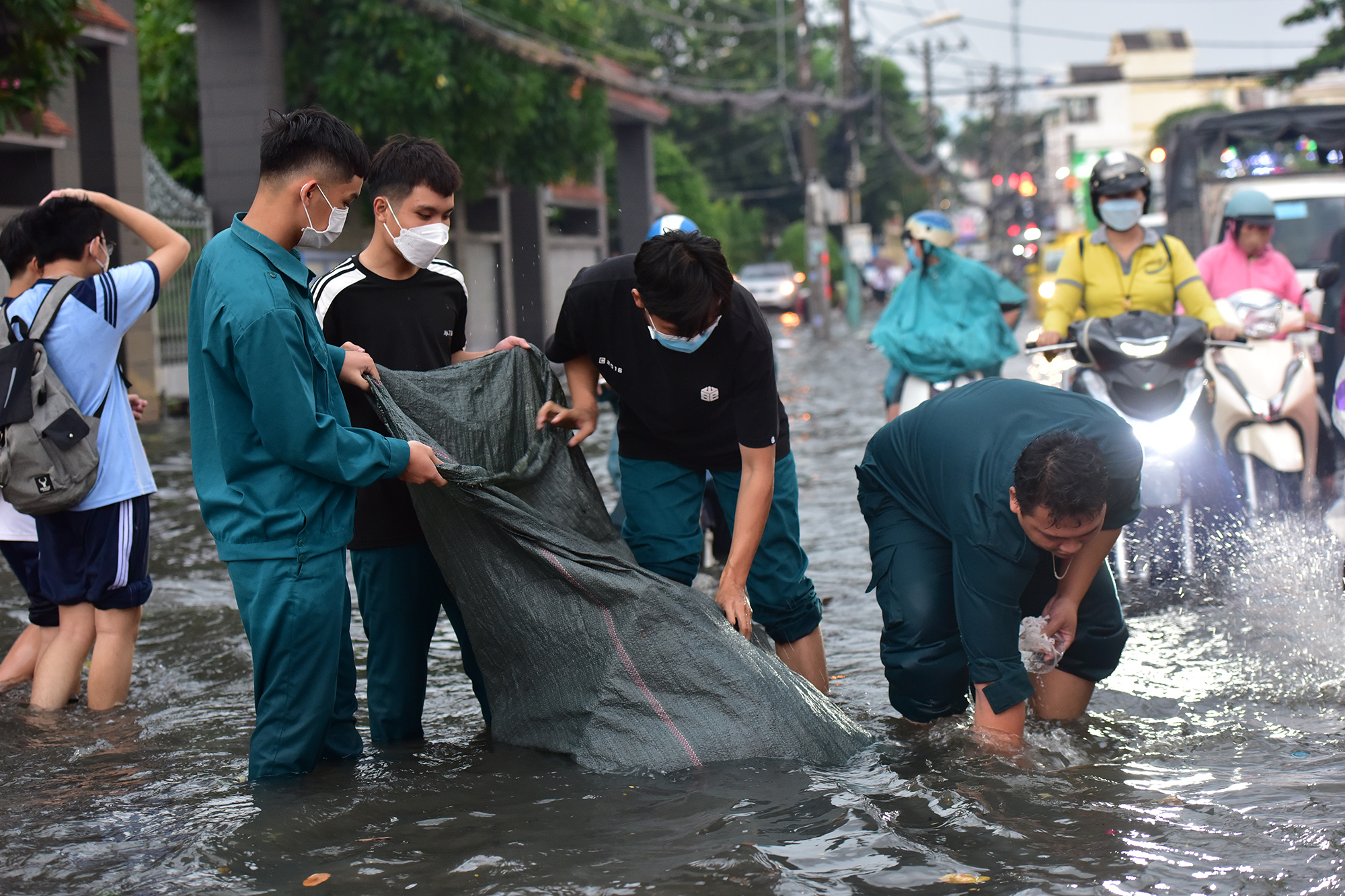 Lực lượng dân quân tự vệ phường Phước Bình chia nhau từng miệng cống để vớt nhiều bao rác lớn, khơi thông dòng chảy.