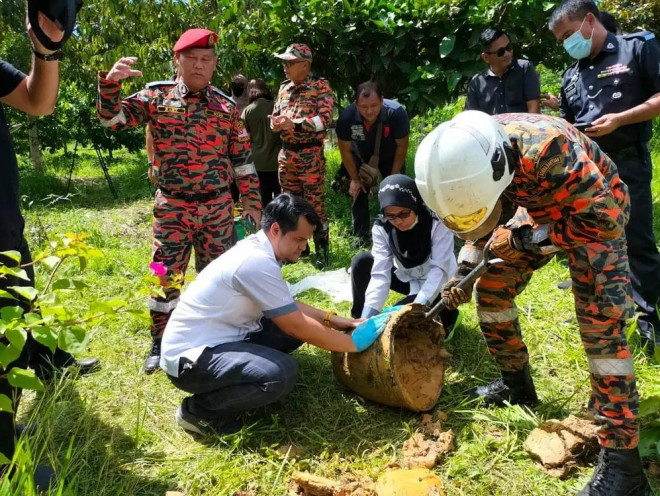 Nhân viên sở cứu hỏa ở Sepupok - Malaysia đang kiểm tra một mảnh vỡ - Ảnh: MALAYSIA NEW AGENCY