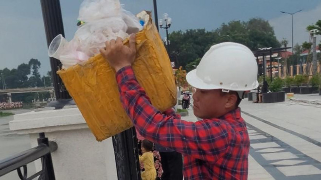 Nam thanh niên vô tư ném từng thùng rác xuống sông Sài Gòn, bất chấp sự ngăn cản của người dân. Ảnh: Người dân cung cấp