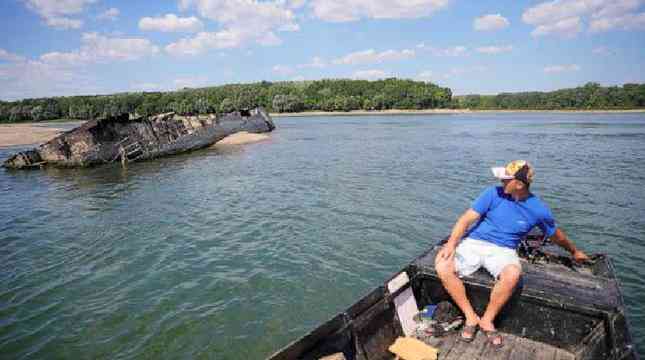 Một ngư dân Serbia đi qua một con tàu đắm. (Ảnh: Reuters)