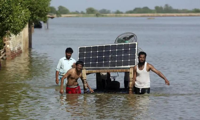 Người dân mang đồ đạc ra khỏi căn nhà bị ngập lụt của họ ở huyện Jaffarabad, tỉnh Baluchistan (Pakistan). Ảnh: AP