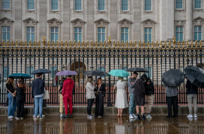 Người dân đội mưa đứng bên ngoài điện Buckingham sau khi nghe tin nữ hoàng qua đời. Ảnh: THE NEW YORK TIMES