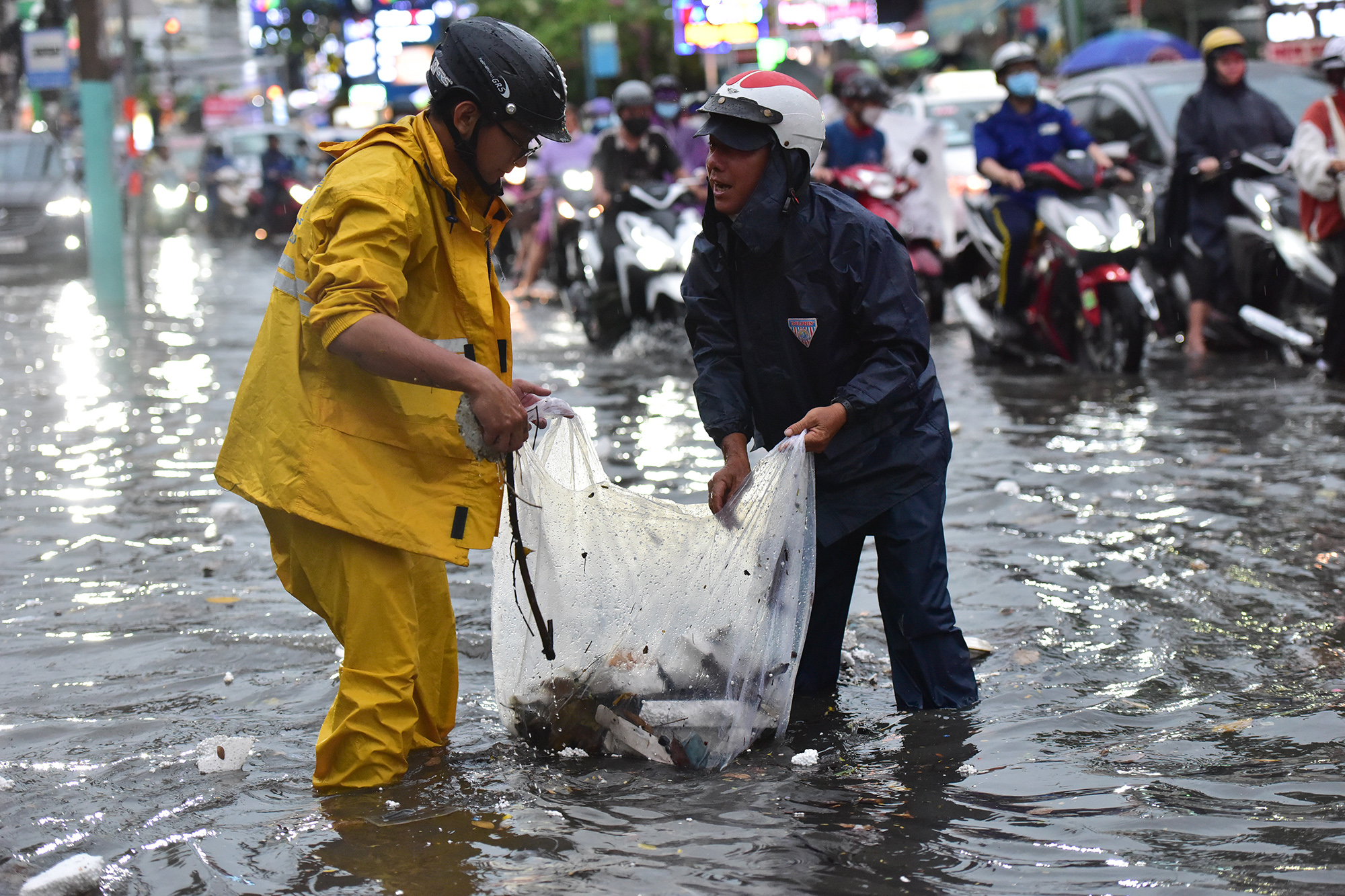 Một đoạn dài hơn 200m đường Đỗ Xuân Hợp, cùng đường số 8, 9, phường Phước Bình nước ngập sâu, kéo dài. Nhân viên công ty thoát nước và người dân liên tục vớt rác từ những miệng cống để nước thoát.