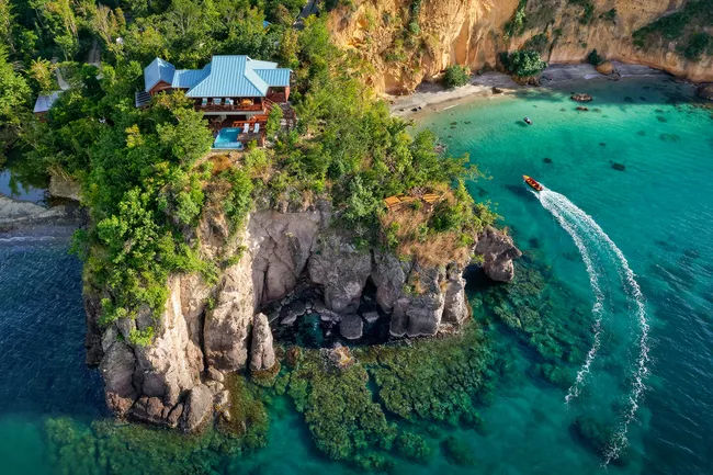 4. Secret Bay, Dominica: Nằm trên sườn núi tuyệt đẹp trong khu rừng nhiệt đới nhìn ra vùng biển Caribe, 6 biệt thự trên cây của Secret Bay là đỉnh cao của sự sang trọng thoải mái, mang đến sự riêng tư chưa từng có giữa cảnh quan hoang sơ của đảo Dominica. Du khách có hồ bơi riêng trong biệt thự của mình hoặc đi xuống bãi biển. Nơi đây có thể nhìn ra biển và núi, cửa sổ kính trong suốt từ trần đến sàn và cửa gấp tạo ra sự chuyển tiếp liền mạch trong nhà - ngoài trời, quản gia, nhân viên hướng dẫn, hướng dẫn viên và đầu bếp riêng. Khu nghỉ dưỡng tập trung vào sức khỏe, đi kèm nhiều trải nghiệm độc đáo, bao gồm lặn biển ban đêm, săn cá sư tử, các buổi hòa nhạc riêng, lớp học nấu ăn. Ảnh: Secret Bay.