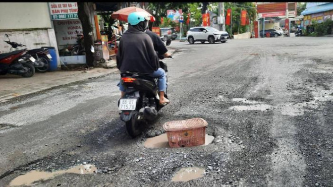 Để cảnh báo "ổ gà", người dân dùng sọt rác nhựa đặt ngay tại ổ gà. Ảnh: Quang Phương.