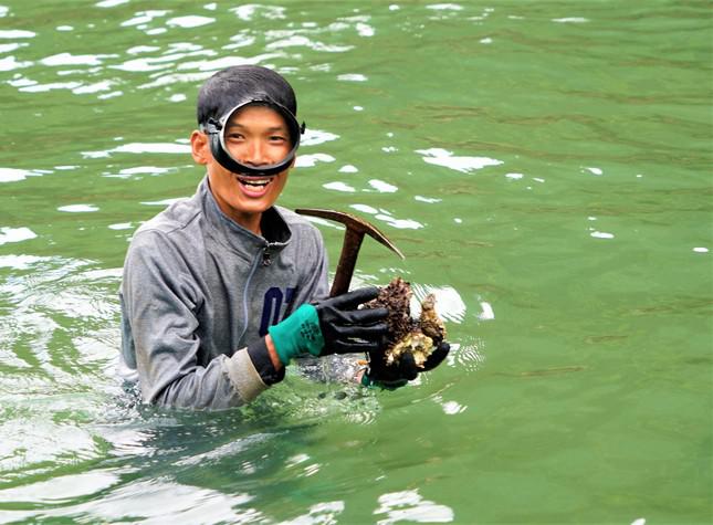 Anh Dũng dần trồi lên cùng chiếc rìu, tay cầm mấy cục đá màu đỏ sẫm, màu vàng cát và cả màu nâu nhạt, bên ngoài mọc đầy gai nhọn như quả chôm chôm