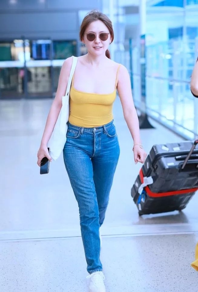 Nữ diễn viên Nhiệt Y Trát xuất hiện ở sân bay với trang phục gồm áo hai dây cổ sâu kết hợp với quần jean. 
