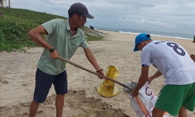 Người dân ra biển Tam Thanh xúc cát để chèn mái.