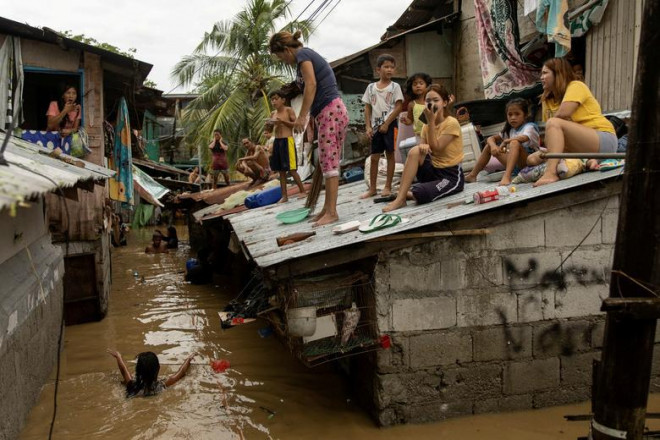 Người dân ngồi trên mái nhà trước cảnh lũ lụt ập đến do siêu bão Noru ở&nbsp;San Miguel, tỉnh Bulacan, Philippines, ngày 26/9.