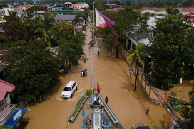 Người dân tại thị trấn San Miguel, tỉnh Bulacan, Philippines lội nước khi tham gia giao thông sau bão Noru. Ảnh AP.&nbsp;