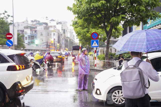 Lực lượng chức năng vất vả điều tiết giao thông dưới trời mưa ở nút giao Nguyễn Huy Tưởng - Ngụy Như Kon Tum.