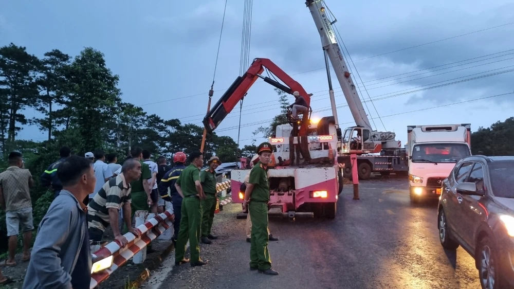 Nhân lực, phương tiện được huy động đến đưa xe khách bị lật lên phía trên. Ảnh: T.T