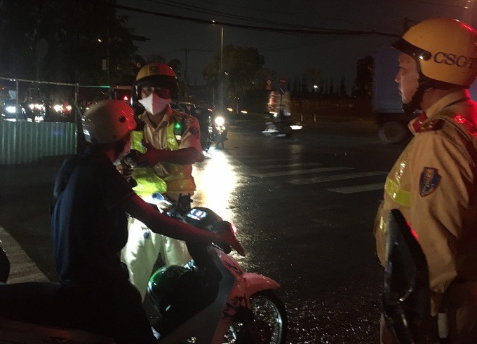 Cảnh sát kiểm tra một người lái xe máy vi phạm nồng độ ở giao lộ Lã Xuân Oai - D2, TP Thủ Đức, tối 2/7. Ảnh: Đình Văn