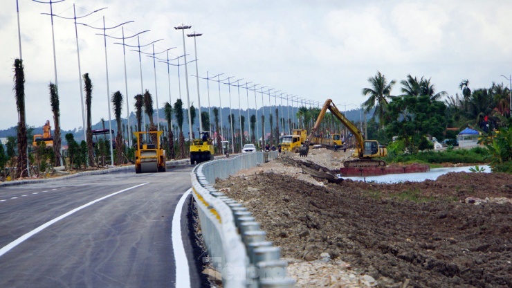 Hàng trăm công nhân và phương tiện, máy móc được huy động hoàn thiện lan can, trồng cây, gia cố hành lang tuyến đường dẫn.