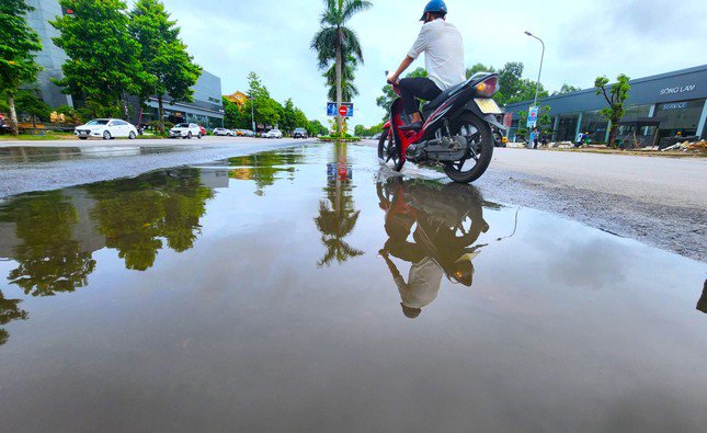 Hai bên mặt đường đã thảm cao, trong khi khoảng giữa không được làm tạo thành những vũng nước lớn.