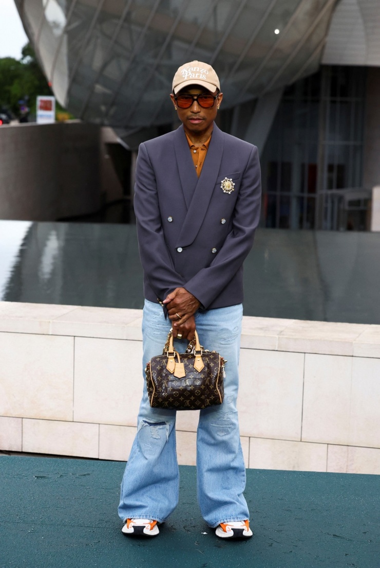 Giám đốc sáng tạo dòng thời trang nam của Louis Vuitton - Pharrell Williams - thể hiện tinh thần thể thao cổ điển với đôi sneakers điểm màu cam neon và túi speedy nổi tiếng của nhà mốt Pháp. Ảnh: Reuters