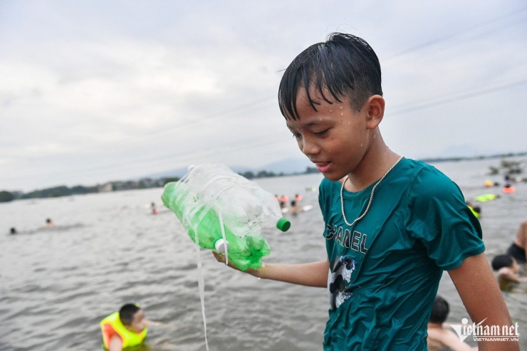 Một bé trai mang theo chiếc phao làm bằng những chai nhựa rỗng buộc lại với nhau.