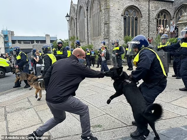 Một người biểu tình bị chó nghiệp vụ cắn vào tay (ảnh: Daily Mail)