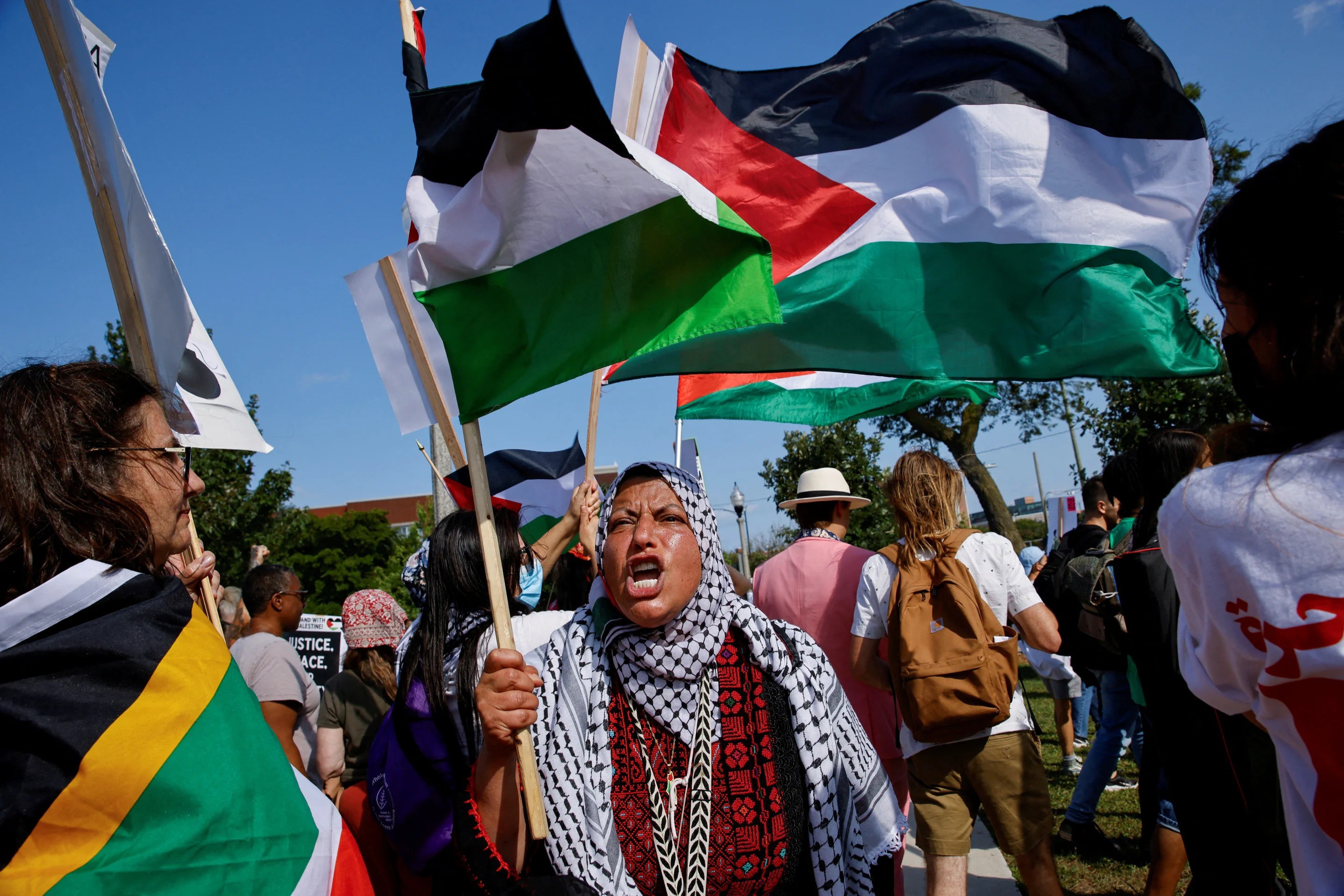 Người biểu tình cầm cờ, mặc áo có thông điệp ủng hộ người Palestine. Ảnh: Reuter/Getty