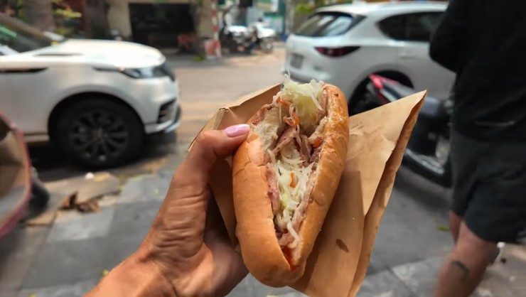 Chiếc bánh mì mà vị khách Tây thưởng thức có lớp vỏ giòn rụm, phần nhân gồm thịt xá xíu, pate và dăm bông, giá 25.000 đồng