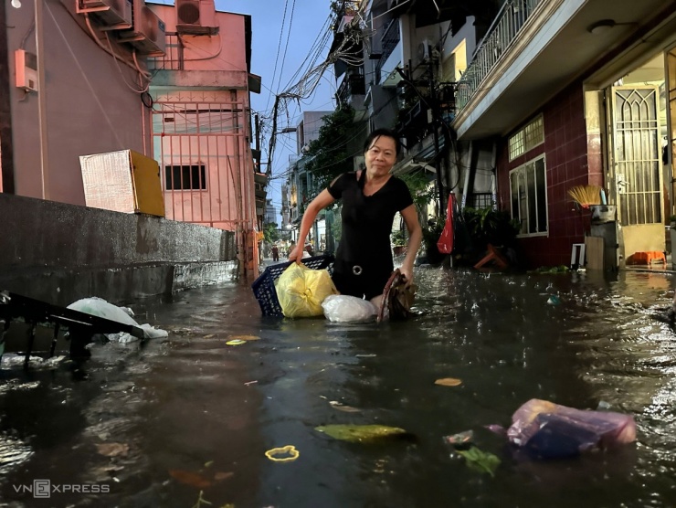 Ở khu vực trung tâm thành phố, hẻm 366 Chu Văn An, quận Bình Thạnh, ngập hơn nửa đầu gối, người dân phải khơi thống cống, dọn rác trôi nổi để nước thoát nhanh.