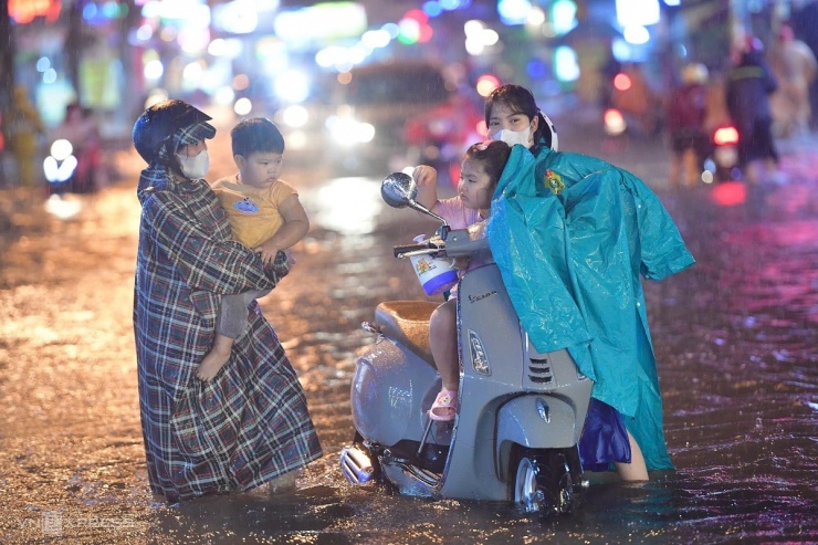 Chị Nguyễn Thị Nga TP Thủ Đức cùng em gái và hai cháu đi chơi lễ, trên đường về xe bị chết máy trên đường Nguyễn Duy Trinh. Chị phải ẵm một bé cho em gái dắt xe qua đường ngập.
