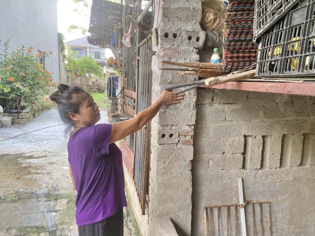 Bà Oanh đặt bàn tay vào điểm nước lũ chạm đến trong đợt lũ lụt vừa rồi tại Chương Mỹ.