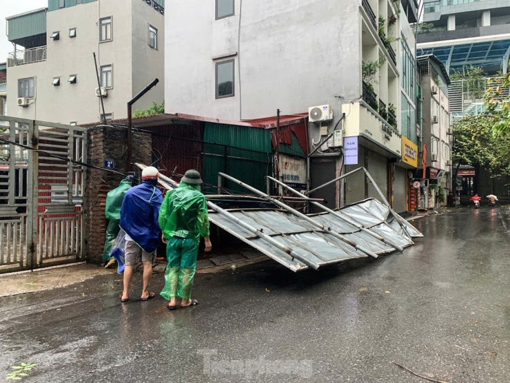 Một biển hiệu lớn bằng tôn trên đường Dịch Vọng đã bị gió giật mạnh quật đổ.