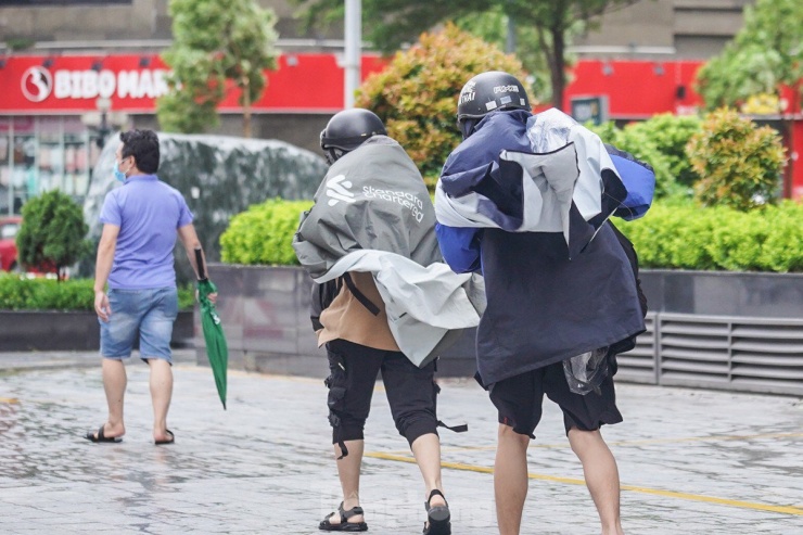 Hai bạn trẻ chới với trong gió, áo mưa bay phần phật.