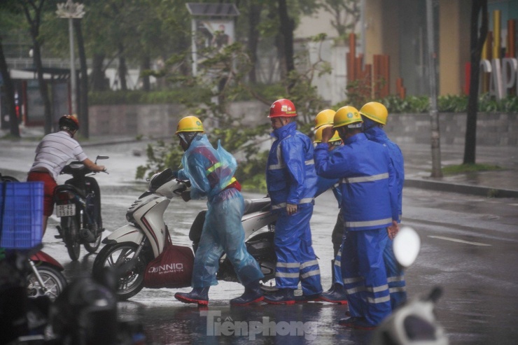 Gió quá mạnh, phải cần đến 6 người mới có thể giúp một chiếc xe di chuyển vào nơi an toàn.