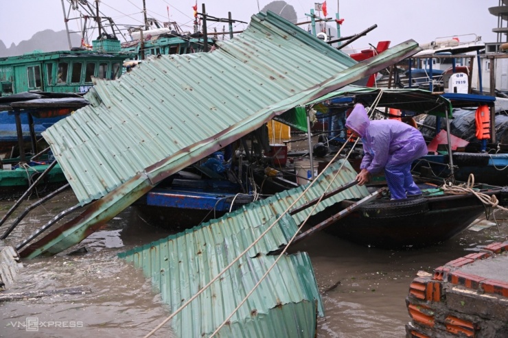 Quảng Ninh cũng gánh nhiều thiệt hại do bão. Những tấm tôn bay đè lên thuyền tránh bão bên cảng Cái Rồng, huyện Vân Đồn, khiến người dân phải đội mưa dọn dẹp. Ảnh: Giang Huy