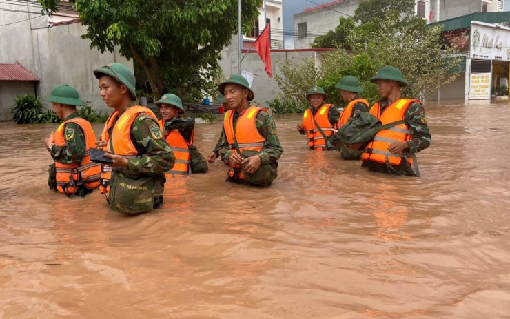 Cán bộ, chiến sĩ lực lượng vũ trang vượt qua đoạn đường ngập sâu trên QL 31 đến giúp chính quyền, nhân dân xã Phì Điền (Lục Ngạn) khắc phục hậu quả mưa bão. 