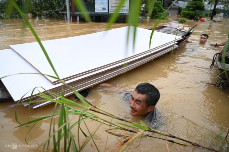 Người dân dùng thuyền đưa tài sản, hàng hoá ra khỏi khu vực ngập ở phố Chương Dương Độ.