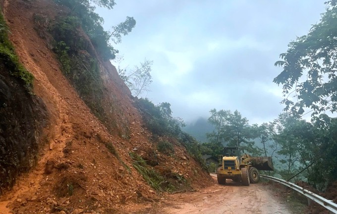 Máy xúc san gạt các vị trí sạt lở để lực lượng cứu hộ tiếp cận hiện trường. Ảnh: ĐL