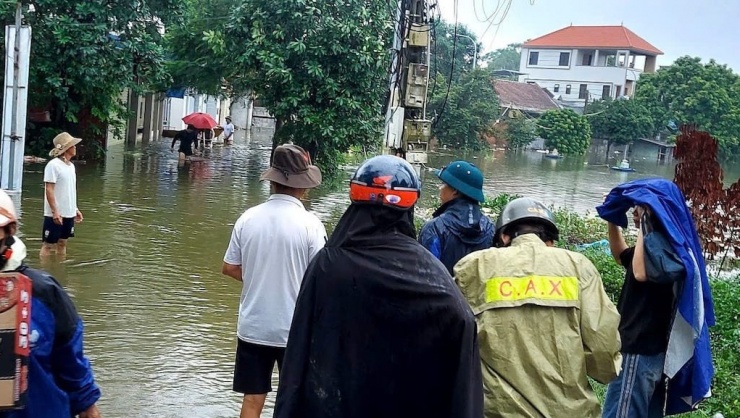 Một số đoạn đường tại Thạch Thất ngập sâu, học sinh nhờ sự hỗ trợ của lực lượng công an để đi qua điểm ngập tới trường. Ảnh: Phương Đỗ.