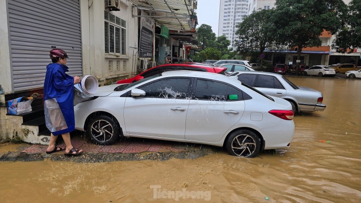 Một chủ xe tranh thủ xuống rửa vết bùn đất còn bám trên xe. Ảnh: Hoàng Mạnh Thắng.