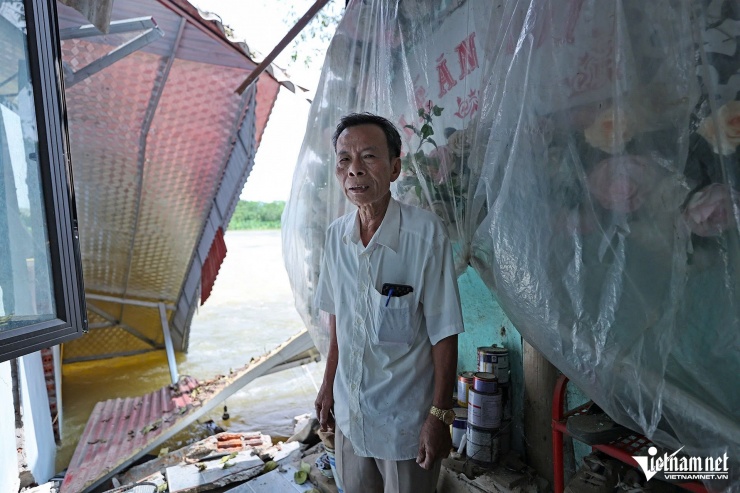 Trưởng thôn Phạm Văn Tiến trong căn nhà bị lũ cuốn phăng một nửa. Ảnh: Lê Anh Dũng 