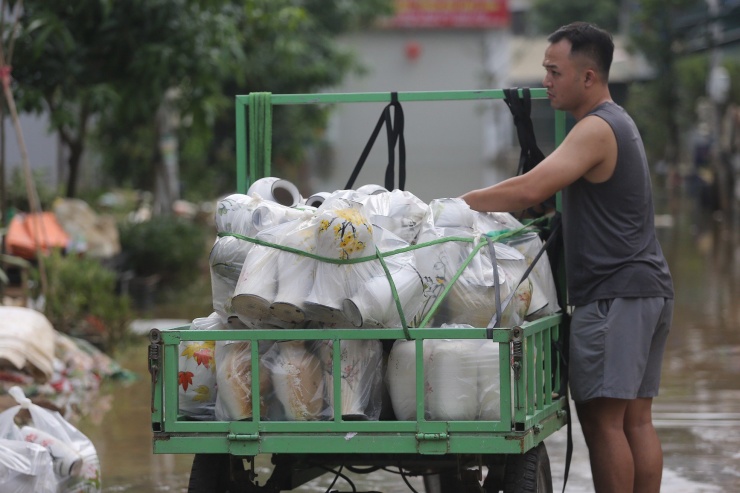 Người dân vận chuyển sản phẩm gốm ra khỏi vùng ngập úng.