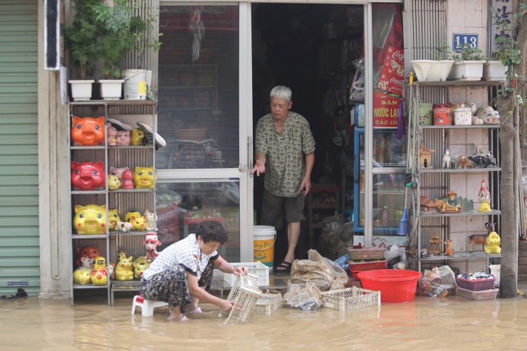 Một gia đình tranh thủ lau rửa các sản phẩm, đồ dùng khi nước lũ rút được một ít.