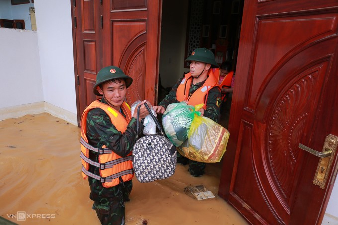 Trung tá Ngô Anh Quyến, Phó Chủ nhiệm chính trị Lữ đoàn công binh 575, Quân khu 1 (bên phải) và đồng đội hỗ trợ người dân ở vùng cô lập tại xóm Rừng Vầu, phường Quang Vinh, TP Thái Nguyên đến nơi an toàn, sáng 10/9. Ảnh: Thanh Nga